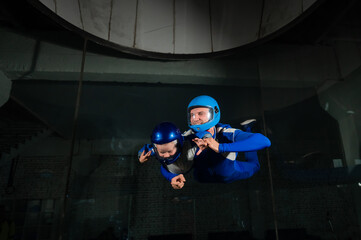 Fototapeta na wymiar A man teaches a boy to fly in a wind tunnel. Lack of gravity.