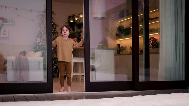 happy redhead kid opens the wooden sliding doors during winter holidays