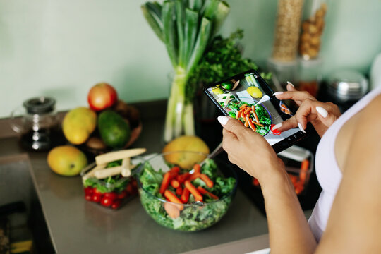 Close-up of a girl's hand taking a photo on her phone. A young woman, a culinary blogger, cooks in her home kitchen and takes photos on her smartphone.