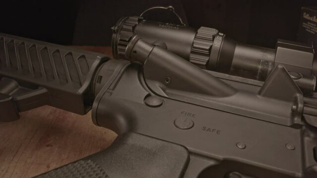 High angle dolly in towards loaded AR-15 assault rifle with a small amount of ammunition in the foreground