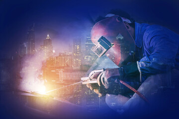 Welding worker welding steel structure with modern building in big city at background for...