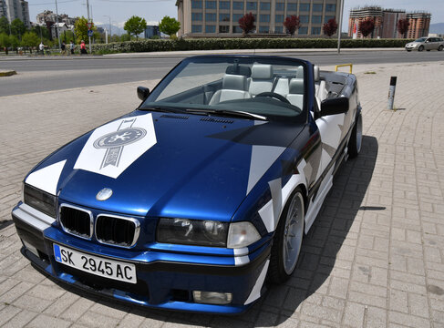 View of the sport car BMW 3 e36 cabriolet with sport rims and covered with decals parked in the street.
