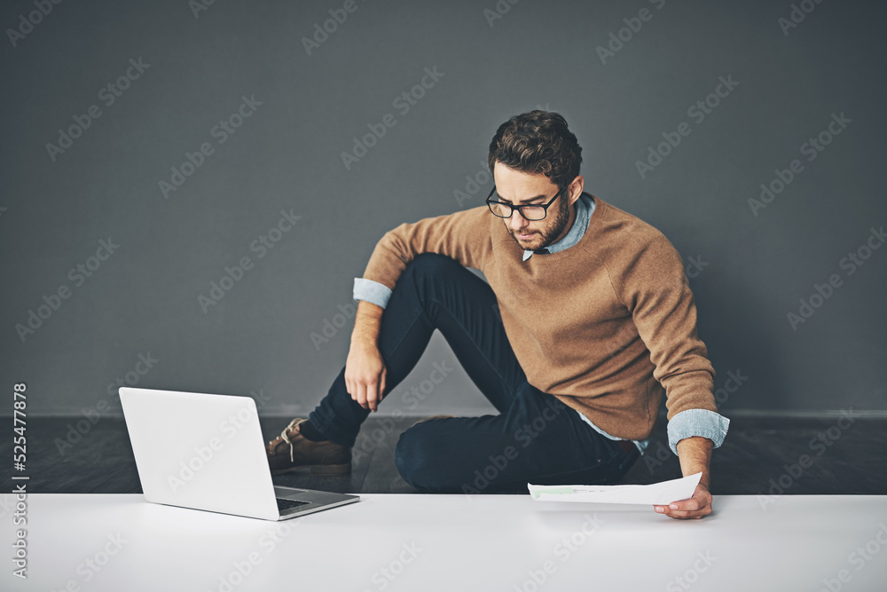 Poster business man working on a laptop, reading a report and going through finance paperwork while sitting