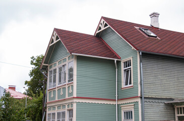Old wooden blue two-storey house immersed in greenery.