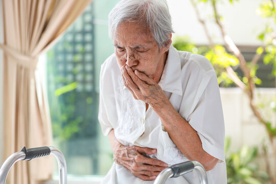 Asian senior woman suffering from abdominal bloating,colic in abdomen,flatulence,accumulation of gas,frequent belching,old elderly with nausea,vomiting,food poisoning,stomach heartburn,gastric problem