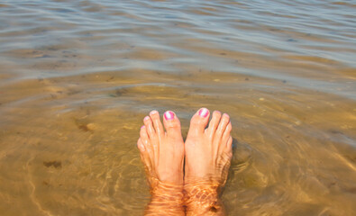 Women's legs, relaxation in the sea wave. Summer vacation concept
