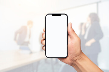 Hand holding blank white screen smartphone with blurred background of business people in modern office