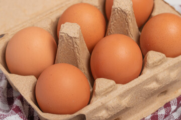 A cardboard box full of fresh chicken eggs on a white background.