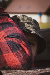 a boy hiding behind his father in a checked shirt. mountain trek