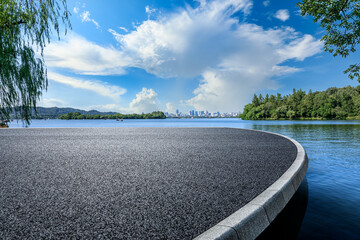 Asphalt road platform and lake with city skyline background - Powered by Adobe