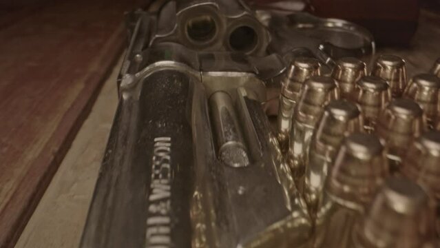 Macro dolly in of revolver barrel pointed at camera and a bunch of .357 cartridges standing next to it