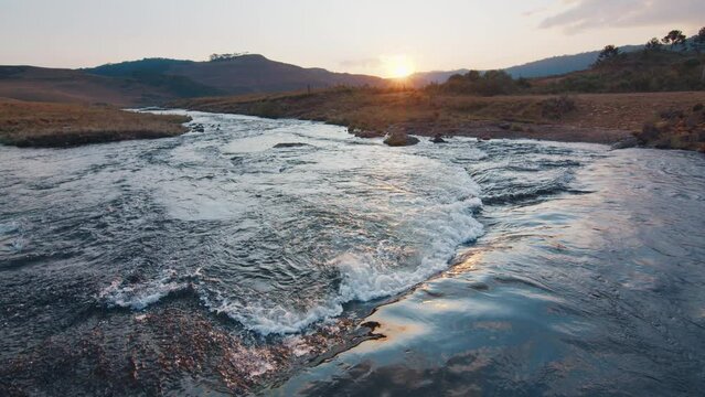 Rapid river flows in Brazilian mountains at sunset