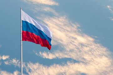 Waving Russian flag against a blue sky with clouds and empty space for text. Room for text....
