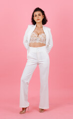 Portrait studio shot of Asian sexy curly hairstyle professional successful businesswoman in white fashionable casual suit with lace lingerie crop top bra standing look at camera on pink background