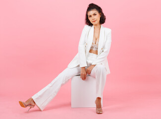 Portrait closeup studio shot Asian young sexy curly hairstyle professional successful businesswoman in white fashion casual suit and lace bra sitting smiling posing on pink background