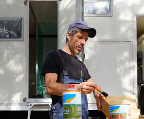 white caucasian man painting wood for the interior of his motor home. Mobile home repair.