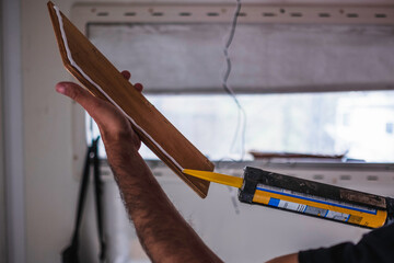 white Caucasian man applying universal mounting glue on timbers for the interior of his motor home. Mobile home repair.