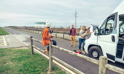 Female mechanic fixing the broken down camper van of a couple going on a trip