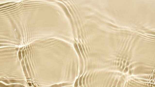 Pure beige water with reflections sunlight in slow motion. Water surface texture. Sun and shadows. Motion clean swimming pool ripples and wave. High quality 4k footage