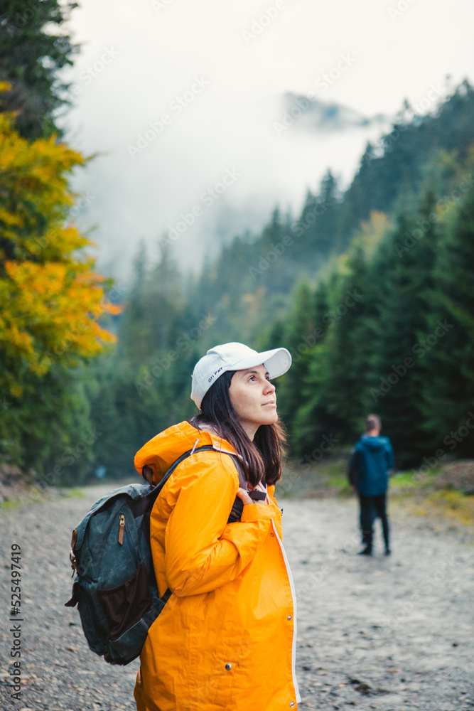 Canvas Prints woman in yellow raincoat hiker in autumn mountains