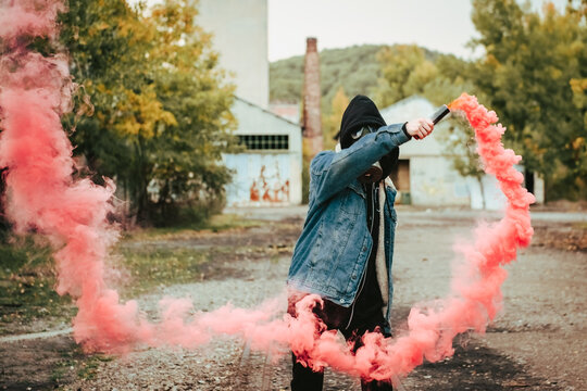Person holding smoke bomb on street