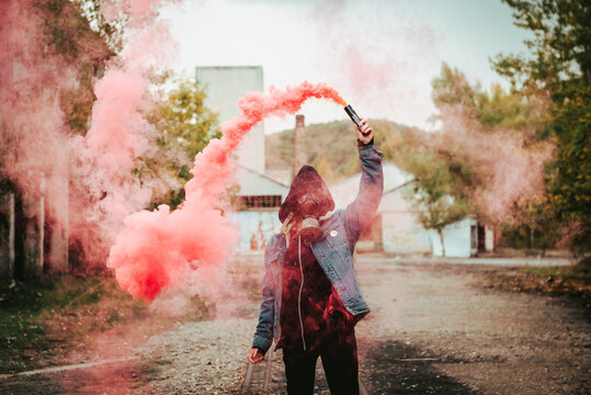 Person holding smoke bomb on street