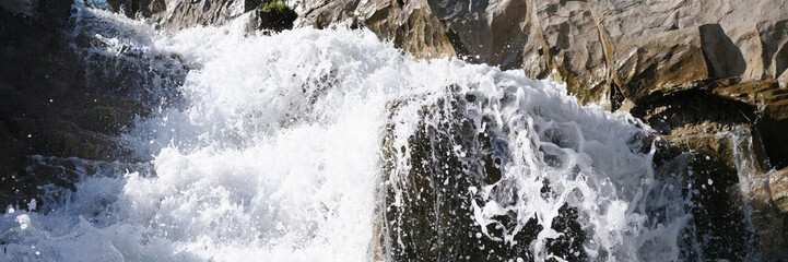 Rapid waterfall with foaming water in rocks background