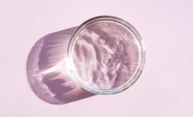 Micellar water serum texture in petri dishes on light pink background cosmetic research concept	
