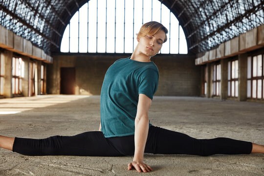 Talented young ballet dancer performing splits in hall