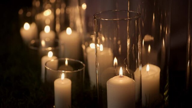 Beautiful candles burn in glass flasks in a dark room. Cool lighting. Blur and defocus. The candle burns in the dark. Aromatherapy, romance and spa relaxation. Soy candles burn at night.