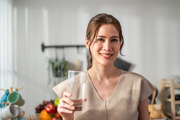 Portrait of Asian attractive woman drink a glass of water in kitchen. 