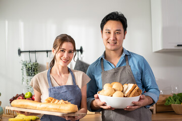 Portrait of Asian young couple hold a bowl of bread and look at camera.