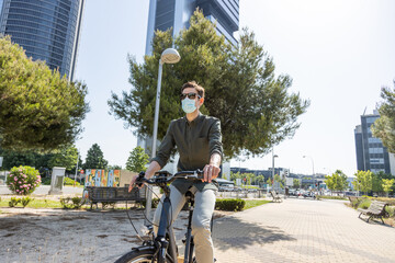 Man in mask riding bicycle along street in city center