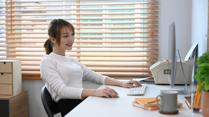 Positive young businesswoman working online, checking business email on computer