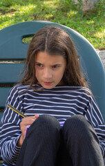 Portrait of a girl writing in her notebook in a pensive attitude.