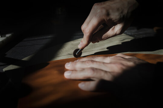 Anonymous man cutting textile in atelier