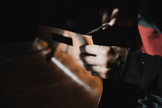 Man varnishing leather in darkness