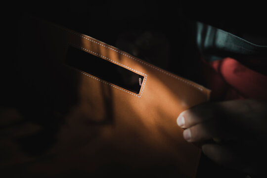 Man varnishing leather in darkness