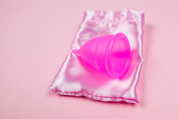Menstrual cup and bag on isolated pink background.