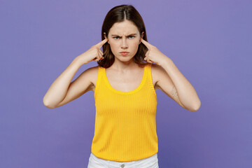 Fototapeta premium Young sad mad woman 20s she wear yellow tank shirt cover ears with hands fingers do not want to listen scream isolated on plain pastel light purple background studio portrait People lifestyle concept