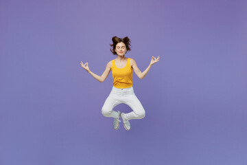 Obraz premium Full body young spiritual tranquil woman wear yellow tank shirt jump high hold spreading hands in yoga om aum gesture relax meditate try to calm down isolated on plain pastel light purple background.