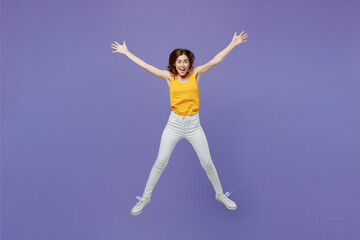 Fototapeta na wymiar Full body young overjoyed surprised excited happy fun woman 20s she wearing yellow tank shirt jump high with outstretched legs hands isolated on plain pastel light purple background studio portrait.