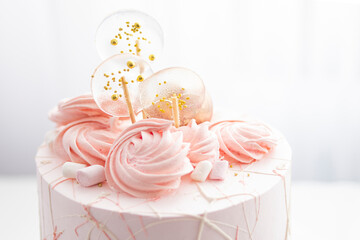 
Pink birthday cake decorated with candies and meringue for a girl for a birthday or Valentine's day on a white background