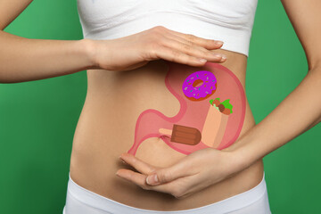 Woman with image of stomach full of junk food drawn on her belly against green background, closeup....
