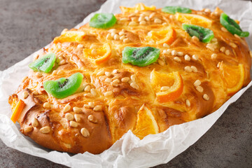 Spanish festive bread coca de sant joan with pine nuts, candied fruit closeup on the paper on the...