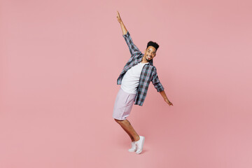 Fototapeta na wymiar Full body young smiling man of African American ethnicity 20s wear blue shirt stand on toes leaning back dance fooling around isolated on plain pastel light pink background People lifestyle concept.