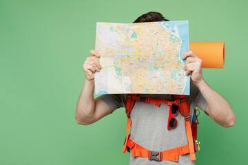 Young traveler white man carry backpack stuff mat cover gace with map isolated on plain green background Tourist leads active healthy lifestyle walk on spare time Hiking trek rest travel trip concept