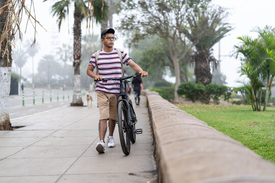 Latin man walking with bicycle