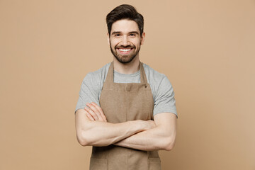 Young smiling happy man barista barman employee in brown apron work in coffee shop hold hand...