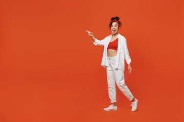 Fototapeta na wymiar Full body young shocked happy woman of African American ethnicity 20s wear white shirt top walking going point index finger aside on workspace area isolated on plain orange background studio portrait.